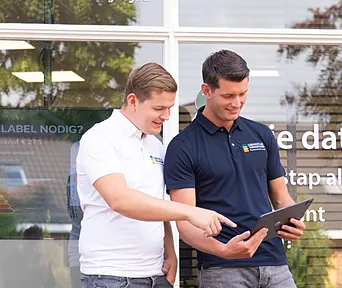Twee adviseurs bekijken samen een tablet voor het kantoor.